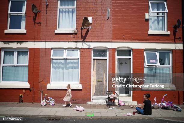 People enjoy the warm and sunny weather relaxing on the pavement outside their homes in the Shorefields area of Liverpool during the Coronavirus...