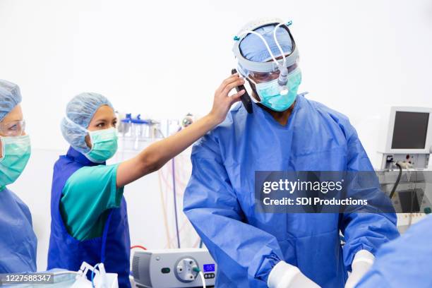 chirurg nimmt dringenden anruf während der operation - op-mundschutz stock-fotos und bilder
