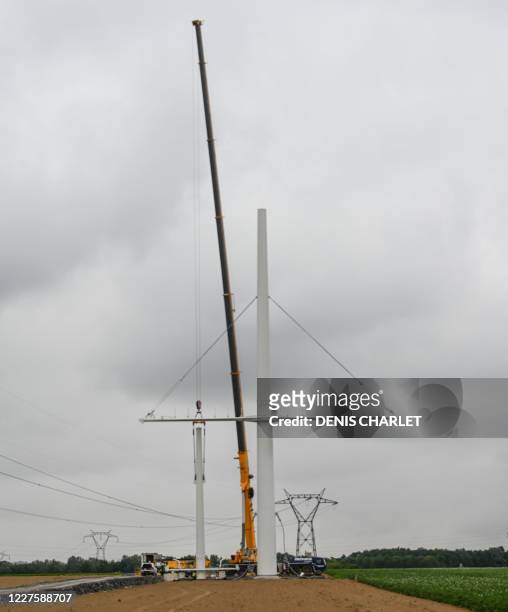 The new electricity pylon is installed by RTE near the town of Flers in Escrebieux, northern France on July 16, 2020. - A central mast and a triangle...