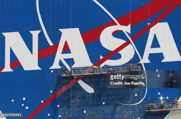 Workers repaint the NASA logo on the Vehicle Assembly Building at the Kennedy Space Center on May 28, 2020 in Cape Canaveral, Florida. SpaceX’s Crew...