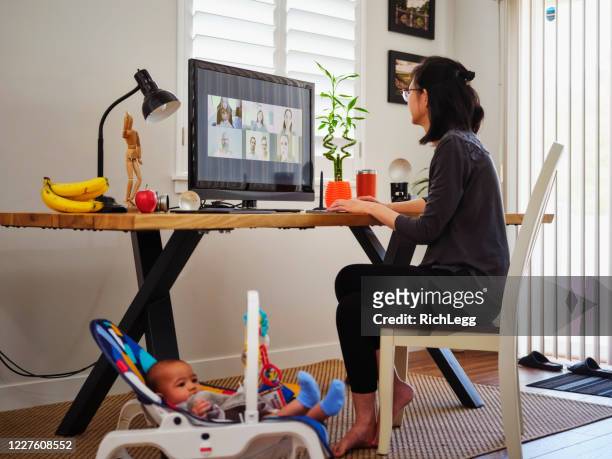 jonge moeder die van huis aan een vraag van de conferentie van de video werkt - mother daughter webcam stockfoto's en -beelden