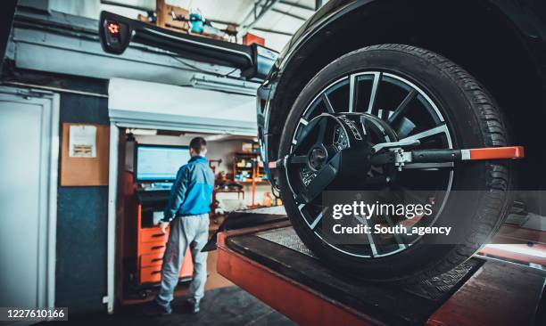 wheel alignment equipment on a car wheel in a repair station - synchronisation stock pictures, royalty-free photos & images