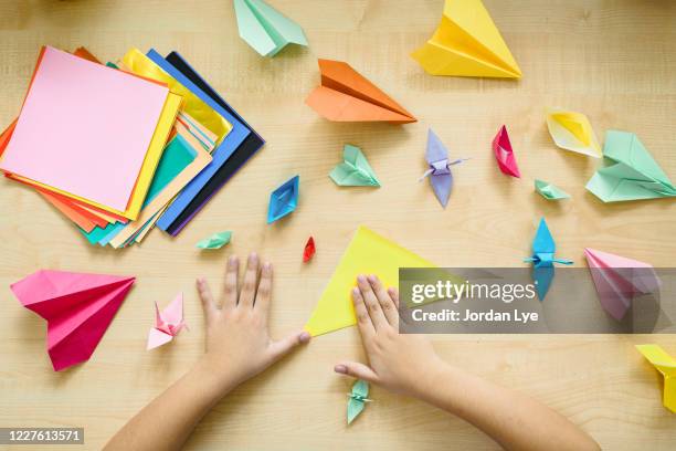 a child's hands folding origami at a table - origami stockfoto's en -beelden