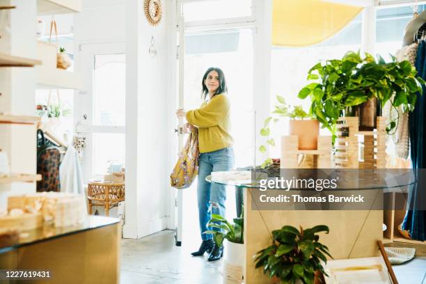 smiling woman walking through door into boutique - chegada imagens e fotografias de stock