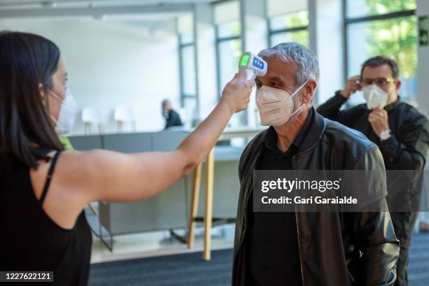 Woman wearing a face mask takes the temperature of a musician from the Basque Symphony Orchestra on May 28, 2020 in San Sebastian, Spain. All regions...