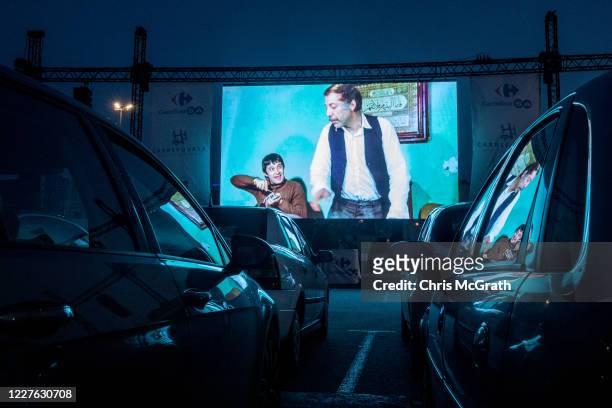 People watch a classic Turkish movie from their cars at a temporary drive-in theatre held in a shopping mall car park amid the ongoing Covid-19...