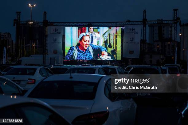 People watch a classic Turkish movie from their cars at a temporary drive-in theatre held in a shopping mall car park amid the ongoing Covid-19...