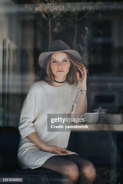 joven hermosa mujer sombrero sentado en el café y mirando fuera - eskisehir fotografías e imágenes de stock