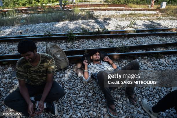 Migrants rest on a railway near Idomeni train station at the border between Greece and North Macedonia on July 16, 2020. - Four years after the...