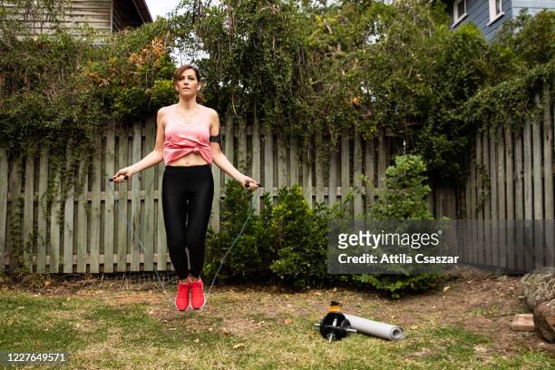 woman jumping with skipping-rope in garden - 縄跳びをする ストックフォトと画像