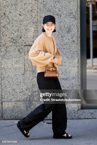 Influencer Maria Barteczko, wearing a black basecap by Asos, a brown oversized sweater by American Vintage, black wide leg trousers by The Row, a...