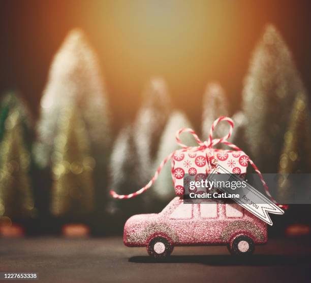 roze auto die kerstgift vervoert. de vakantieachtergrond van kerstmis. - christmas driving stockfoto's en -beelden