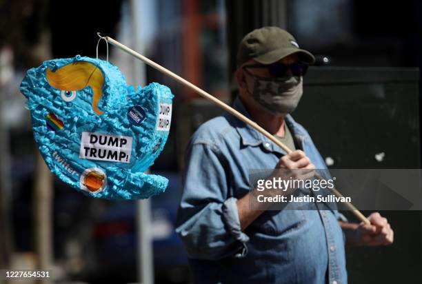 Activist Mike Merrigan holds a piñata shaped like the Twitter logo with hair to look like U.S. President Donald Trump during a protest outside of...