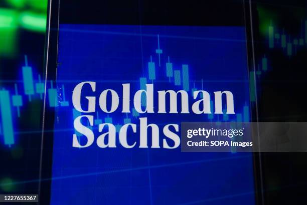 In this photo illustration a multiple exposure image shows a Goldman Sachs logo displayed on a smartphone with stock market percentages on the...