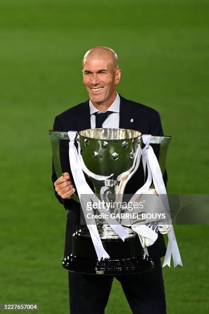 Real Madrid's French coach Zinedine Zidane celebrates winning the Liga title with the trophy after the Spanish League football match between Real...