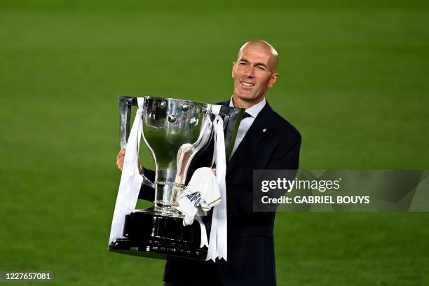 Real Madrid's French coach Zinedine Zidane celebrates winning the Liga title with the trophy after the Spanish League football match between Real...