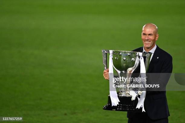 Real Madrid's French coach Zinedine Zidane celebrates with the trophy after winning the Liga title after the Spanish League football match between...