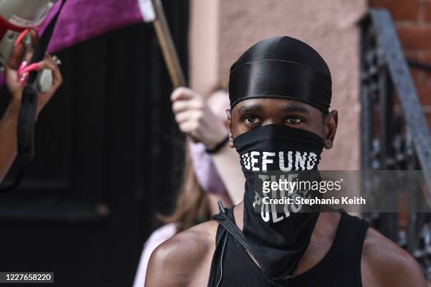 Black trans liberation activist wears a bandana that reads "Defund the Police" in front of the Stonewall Inn on July 16, 2020 in New York City....