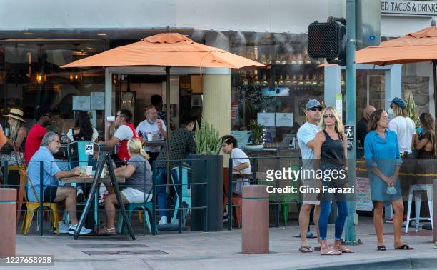As pedestrians ignore the mandatory face coverings order, the outdoor seating at El Patron restaurant is filled in downtown Palm Springs on July 16,...