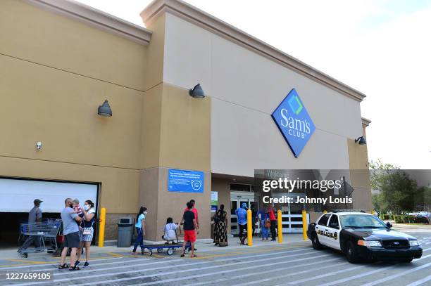 Customers wearing face masks wait in line to enter a Sam's Club store on July 16, 2020 in Miramar, Florida. Some major U.S. Corporations are...