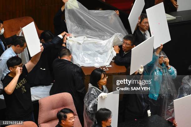 Lawmakers from the ruling Democratic Progressive Party and parliament staffers use boards and sheets to block water ballons thrown by opposition...