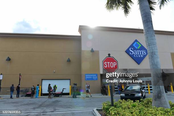 Customers wearing face masks wait in line to enter a Sam's Club store on July 16, 2020 in Miramar, Florida. Some major U.S. Corporations are...