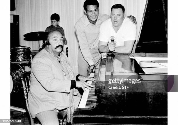 Photo prise le 20 juillet 1970 du chanteur auteur-compositeur Jean Constantin au piano du cabaret "Don Camillo" accompagnant Pierre Colnard, alors...