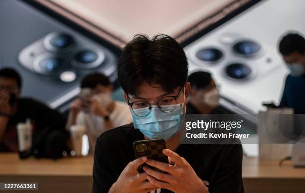 Chinese customer looks at a phone at the official opening of the new Apple Store in the Sanlitun shopping area on July 17, 2020 in Beijing, China....