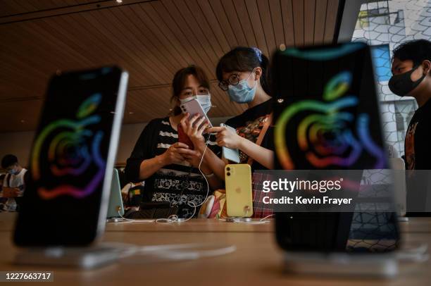 Chinese customers look at iphones at the official opening of the new Apple Store in the Sanlitun shopping area on July 17, 2020 in Beijing, China....