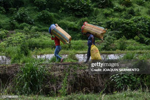 Former FARC guerillas carry their belongings as they arrive at a new reintegration zone in Mutata, Antioquia's Department, Colombia, on July 16, 2020...