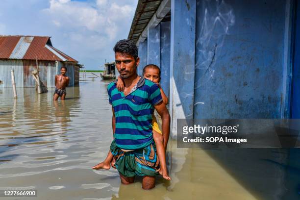 Man carrying a child walks through a flooded street in Bogura. One third of Bangladesh is under water after heavy rains hit the nation. At least 1.5...
