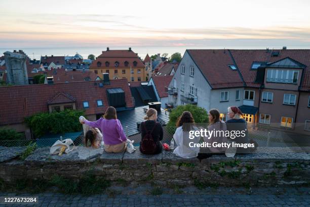 Pixi Ingelse, Andrea Petterson Gomez, Aisha Hassan, Nora Ödmann, Alexandra Eskelinen and Emilia Eskelinen sit along a street in the town of Visby on...