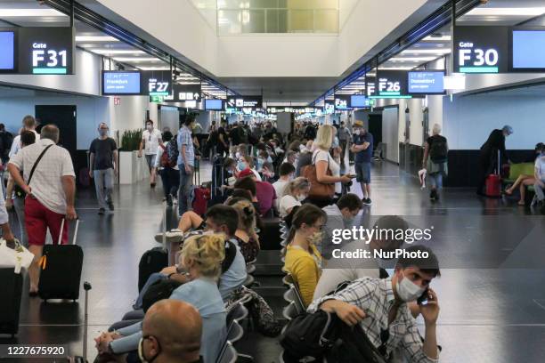 Passengers wearing facemasks, gloves and safety measures are seen on July 15, 2020 at the terminal, F Gates area of Vienna International Airport VIE...