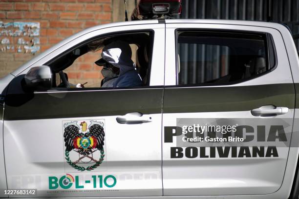 Police officer wearing PPE sits in a police car after exiting the house of a police officer who tested positive for COVID-19 during a door to door...