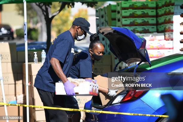 Volunteers load free groceries into cars for people in need at a community food distribution food bank in the Crenshaw neighborhood of Los Angeles,...