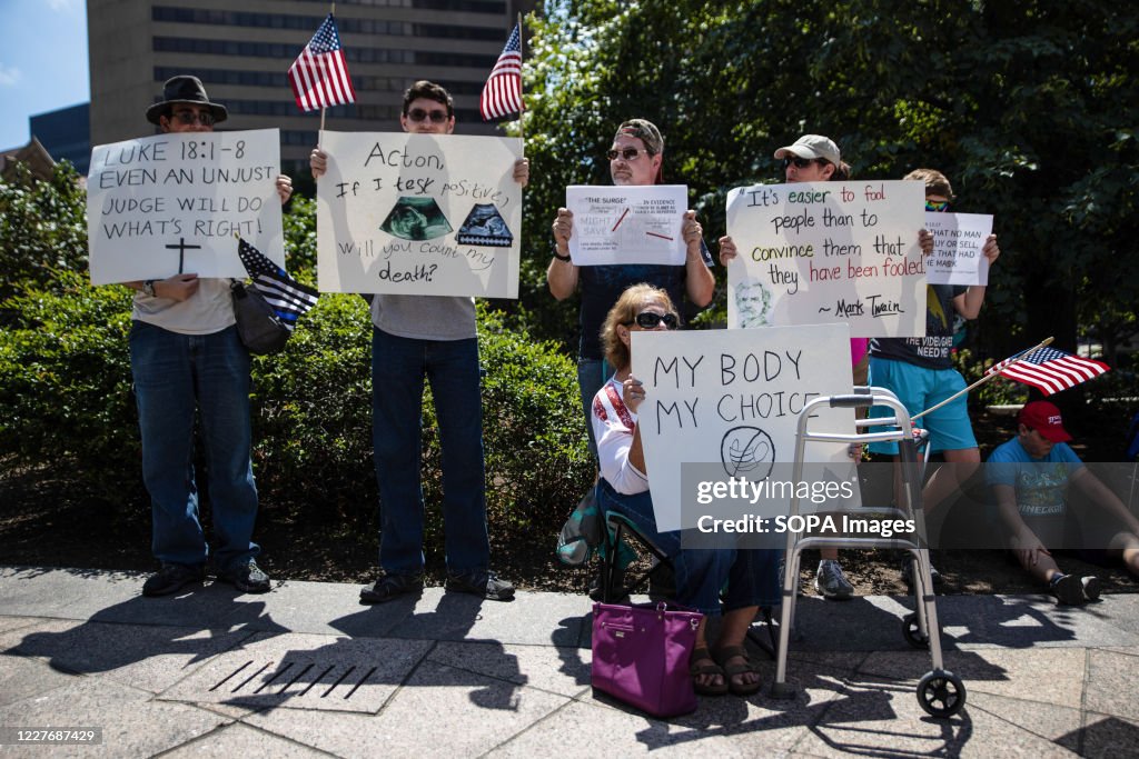 Protesters hold placards during an 'Anti-Mask' rally at Ohio...