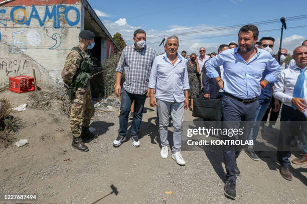Italian Lega Party leader Matteo Salvini passes next to a soldier during his visit to a Roma settlement where hundreds of nomadic people live in very...
