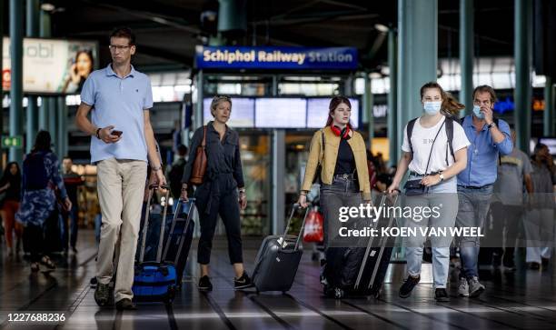 Travelers are seen at Schiphol airport, on July 19, 2020 near Amsterdam. - After coronavirus lockdowns that brought civil aviation to nearly a...