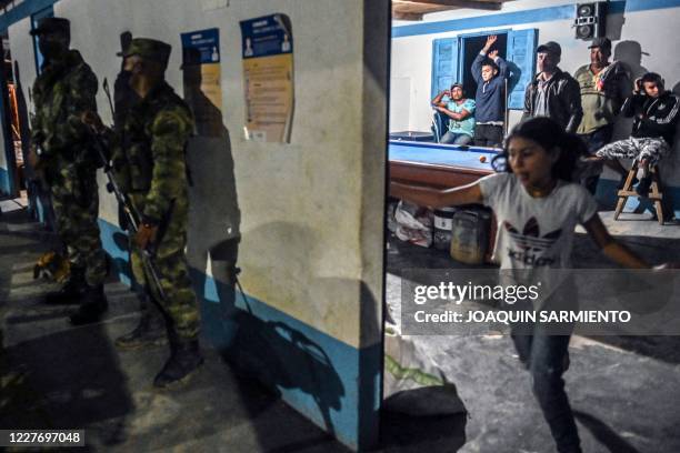 Colombian soldiers stand guard as former FARC guerrillas and locals play billiards in Santa Lucia near Ituango, Antioquia department on July 15 the...