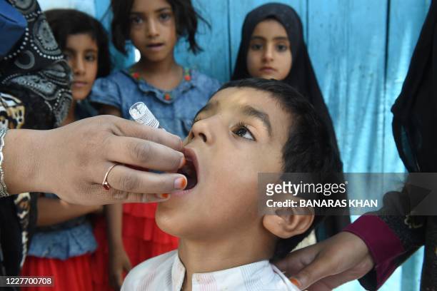 Health worker administers polio vaccine drops to a child during a polio vaccination door-to-door campaign in the outskirts of Quetta on July 20,...