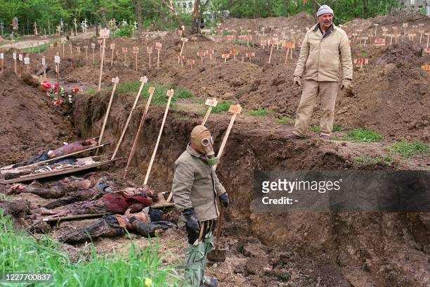 Worker wearing a gas mask arranges corpses into a mass grave in Grozny's cemetery on May 11, 1995. The situation for the population of the Chechen...