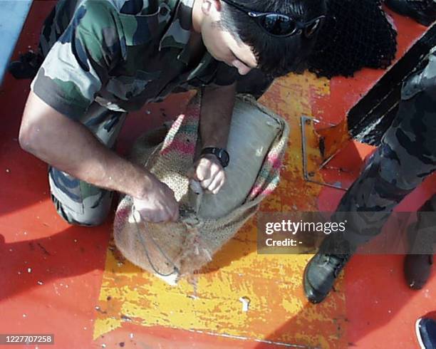 Des membres de la marine nationale manipulent des paquets contenant de la cocaïne, le 28 juillet 2001 au large des côtes de Guyane, à bord du...