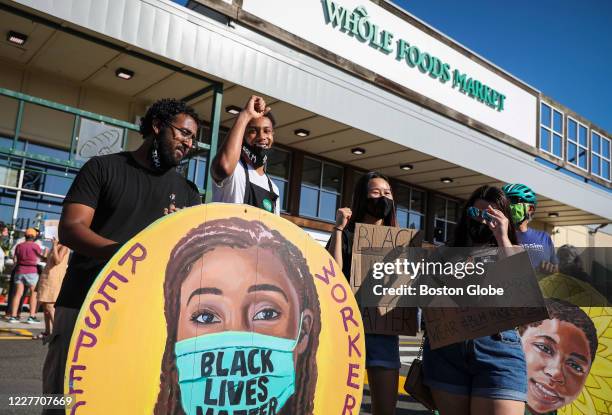 Adam Hermon, left, and Abdulai Barry stand in front of Whole Foods with other employees after getting dismissed from their shift for wearing Black...