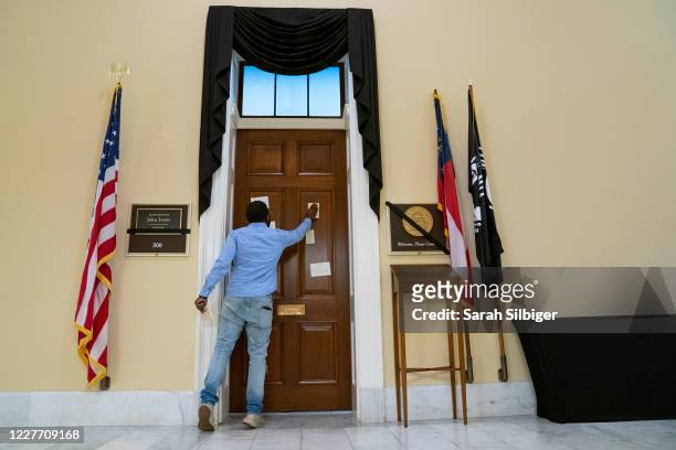 Antwoin Monach, a staff member for Rep. Hank Johnson , places a note on the office door of civil rights activist Rep. John Lewis , who died last...