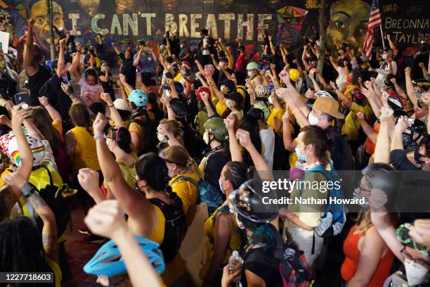 Protesters hold their fists in the air while marching past a mural with George Floyds last words during a march to the Mark O. Hatfield U.S....