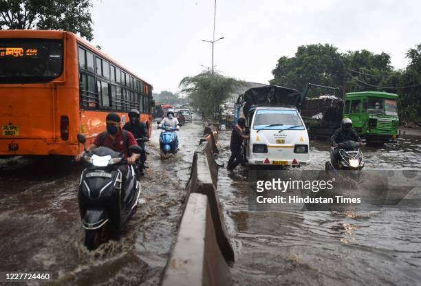 Commuters make their way past heavy water logging after a spell of rain at Anand Parbat, on July 21, 2020 in New Delhi, India. Heavy downpour Monday...