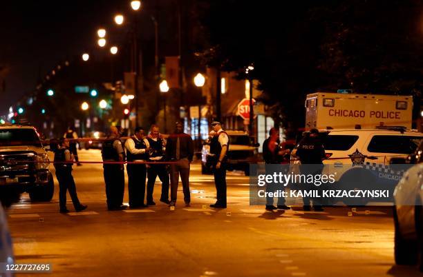 Chicago Police officers investigate the scene of a shooting in Chicago, Illinois, on July 21, 2020. - A shootout outside a funeral left 14 people...