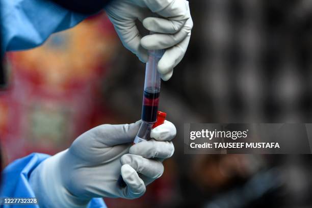 Health worker transfers in a test tube a blood sample donated by a recovered COVID-19 coronavirus patient for plasma at a donation camp in Srinagar...