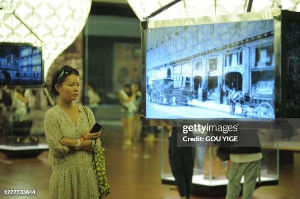 This photo taken on June 3, 2011 shows a visitor looking at items on display at the Louis Vuitton Voyages exhibition in the national museum of China...