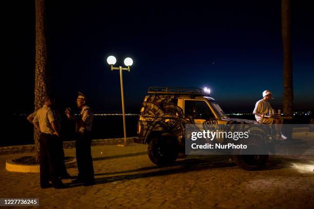 Hammamet, Tunisia, 11 August 2016. A graffiti artist sits on a tagged car while police patrol.